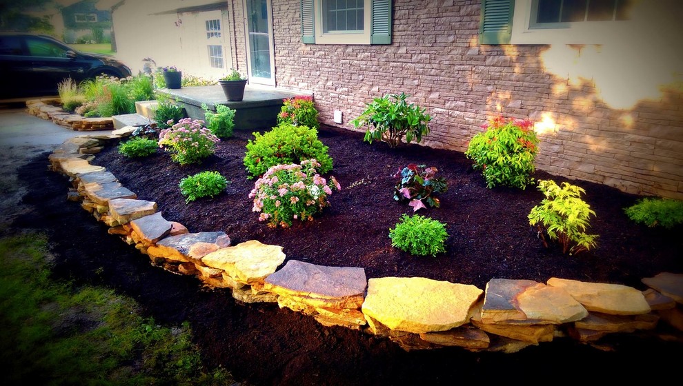 Photo of a mid-sized front yard full sun formal garden for spring in New York with a retaining wall and natural stone pavers.