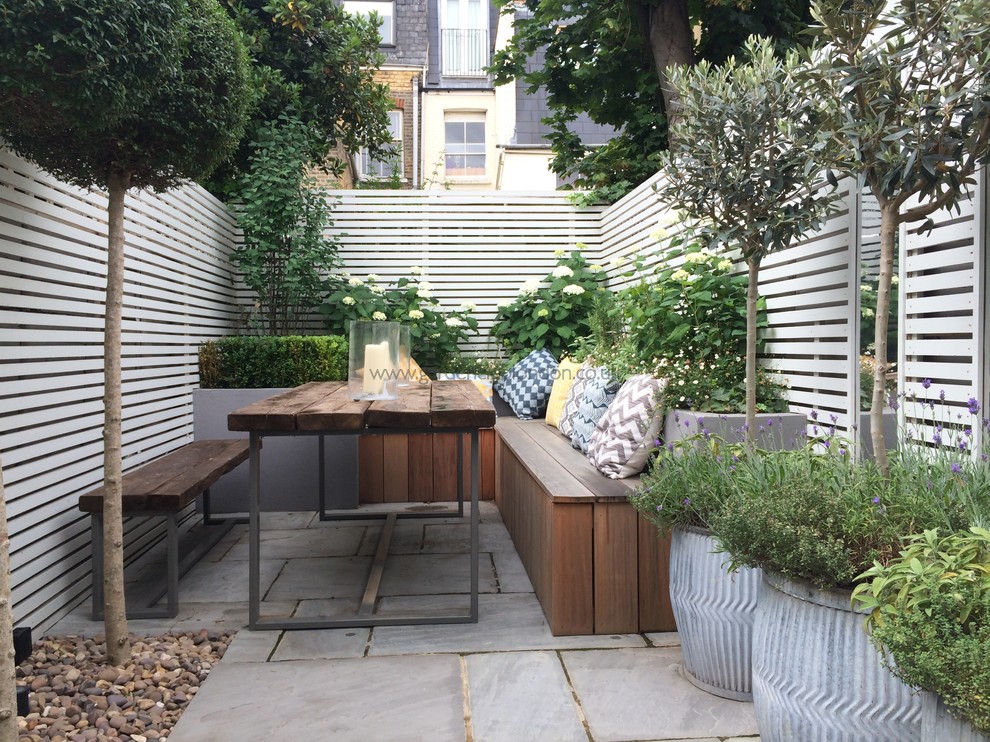 Small modern back patio in London with a potted garden and natural stone paving.