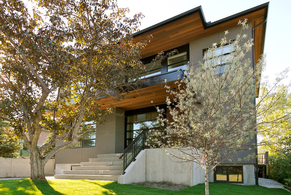 Photo of a mid-sized contemporary two-storey stucco grey exterior in Calgary.