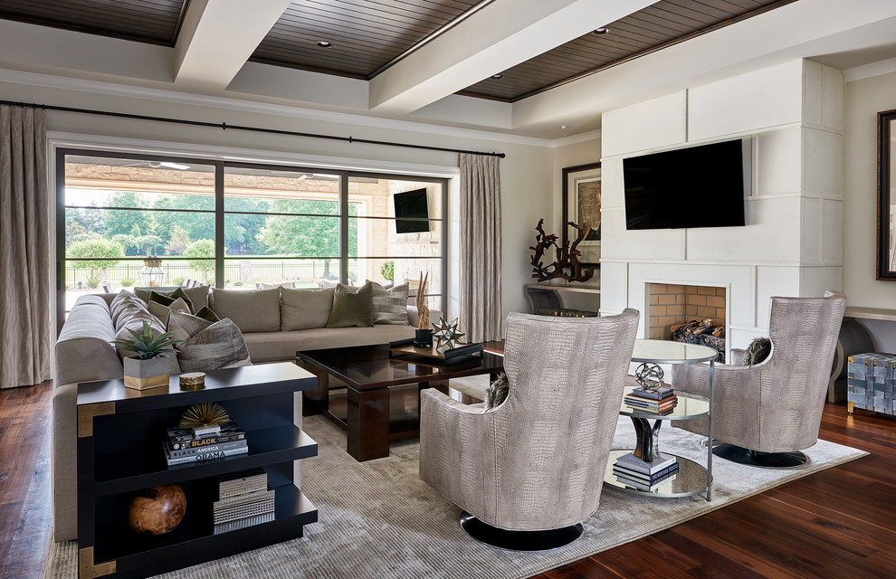 Photo of a mid-sized transitional open concept living room in Charlotte with beige walls, dark hardwood floors, a wall-mounted tv, brown floor, a standard fireplace and a plaster fireplace surround.