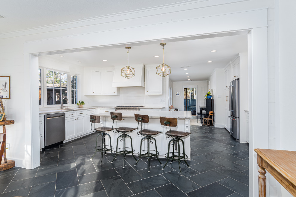 This is an example of a large contemporary l-shaped eat-in kitchen in New Orleans with an undermount sink, shaker cabinets, white cabinets, quartzite benchtops, white splashback, slate splashback, stainless steel appliances, slate floors, with island, black floor and multi-coloured benchtop.