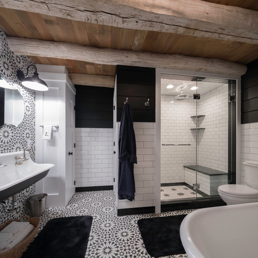 This is an example of a country master bathroom in Philadelphia with black and white tile, black walls, a hinged shower door, a freestanding tub, an alcove shower, a two-piece toilet, cement tile, cement tiles, a trough sink and multi-coloured floor.
