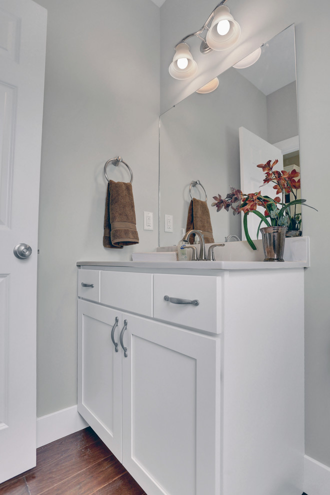 Photo of a large arts and crafts powder room in Other with white cabinets, a two-piece toilet, beige walls, an integrated sink, marble benchtops and medium hardwood floors.