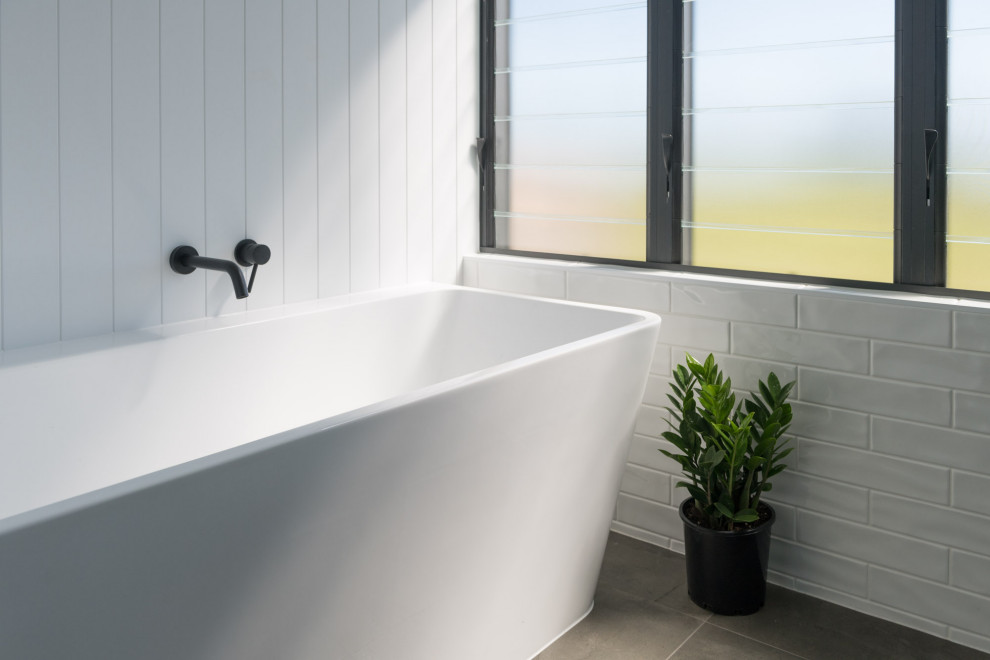 Inspiration for a mid-sized modern kids bathroom in Brisbane with a freestanding tub, white tile, ceramic tile, white walls, ceramic floors, brown floor and panelled walls.