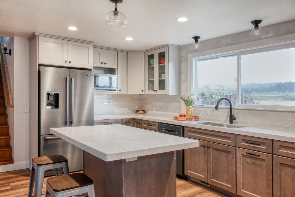 Eat-in kitchen - mid-sized transitional u-shaped light wood floor and brown floor eat-in kitchen idea with an undermount sink, recessed-panel cabinets, medium tone wood cabinets, solid surface countertops, white backsplash, ceramic backsplash, stainless steel appliances, an island and white countertops