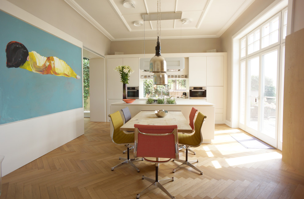 Photo of a mid-sized contemporary kitchen/dining combo in Hamburg with white walls and medium hardwood floors.