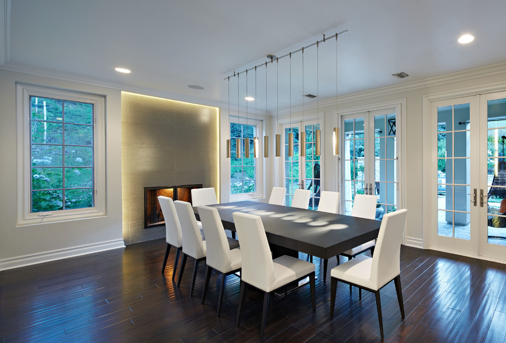 This is an example of a large contemporary open plan dining in Los Angeles with white walls, dark hardwood floors, a standard fireplace and a tile fireplace surround.