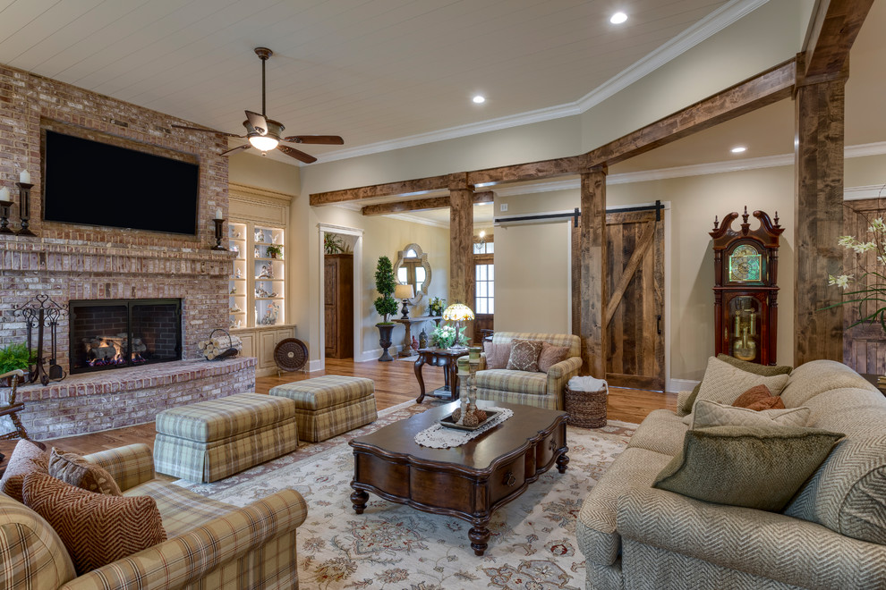 Design ideas for an expansive country open concept living room in Other with a library, beige walls, medium hardwood floors, a standard fireplace, a brick fireplace surround, a built-in media wall and brown floor.