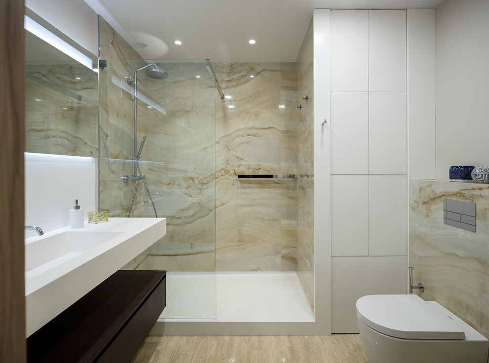 Photo of a mid-sized contemporary 3/4 bathroom in Moscow with flat-panel cabinets, beige tile, porcelain tile, white walls, travertine floors, solid surface benchtops, beige floor, an open shower, white benchtops, dark wood cabinets, an alcove shower, a two-piece toilet and an integrated sink.