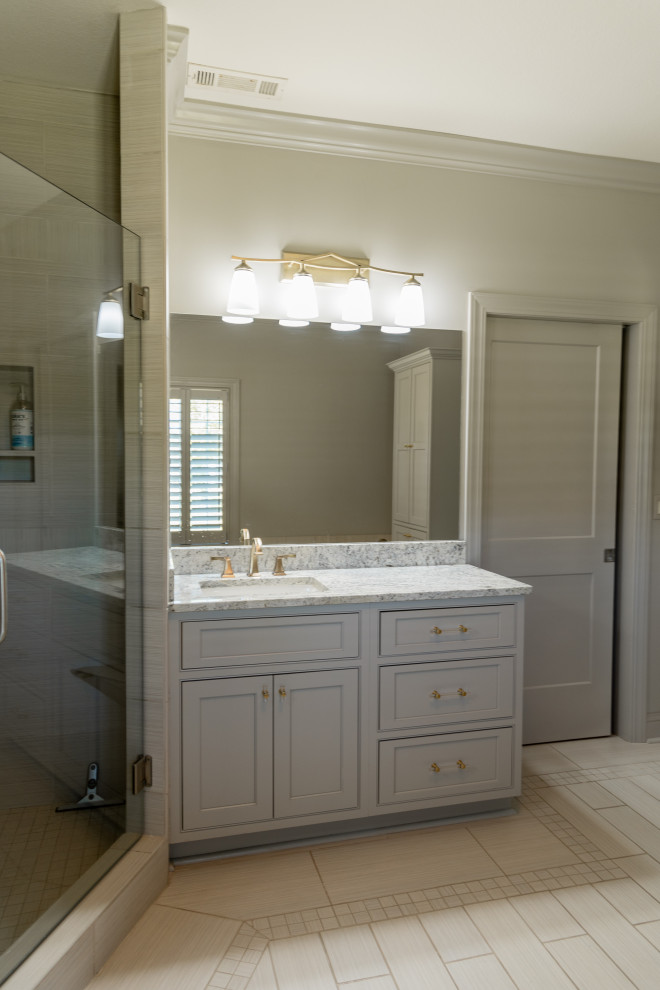 This is an example of a large traditional master bathroom in St Louis with shaker cabinets, grey cabinets, a corner shower, gray tile, ceramic tile, grey walls, ceramic floors, an undermount sink, engineered quartz benchtops, beige floor, a hinged shower door, grey benchtops, a double vanity and a built-in vanity.