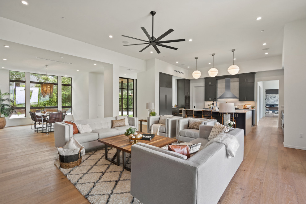 Photo of a medium sized contemporary formal open plan living room in Austin with white walls, medium hardwood flooring, a standard fireplace, a metal fireplace surround and no tv.