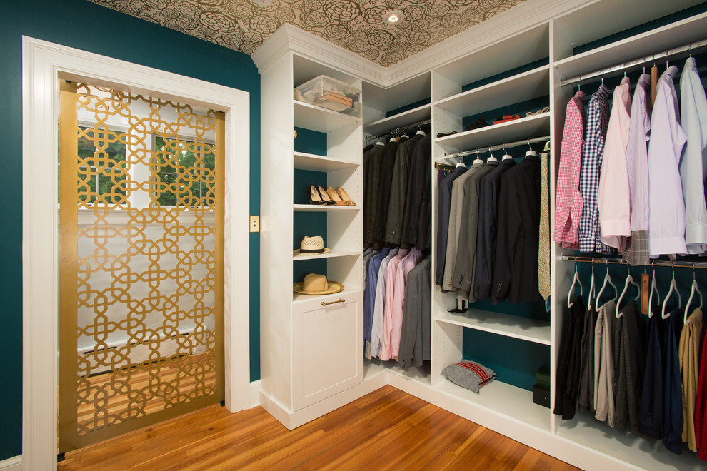 Photo of a transitional gender-neutral walk-in wardrobe in DC Metro with open cabinets, white cabinets, medium hardwood floors and brown floor.