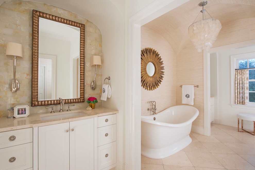 This is an example of a transitional master bathroom in Dallas with an undermount sink, beaded inset cabinets, white cabinets, a freestanding tub, beige tile, stone tile and beige walls.