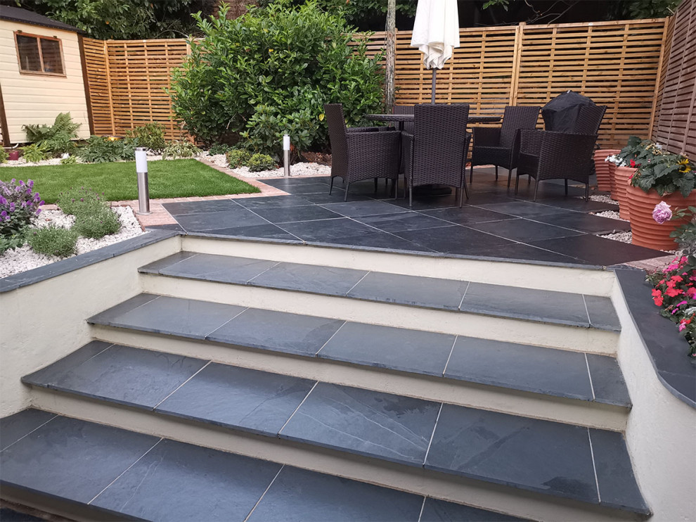 Photo of a medium sized contemporary back patio in Hertfordshire with natural stone paving.