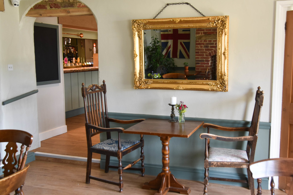 This is an example of a mid-sized country separate dining room in Dorset with green walls, laminate floors and brown floor.