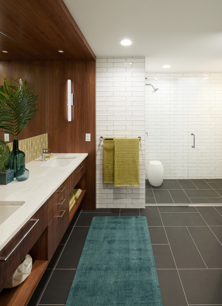 Photo of a mid-sized midcentury master wet room bathroom in Minneapolis with flat-panel cabinets, medium wood cabinets, ceramic tile, white walls, ceramic floors, an undermount sink, engineered quartz benchtops, grey floor, a hinged shower door, white benchtops and white tile.
