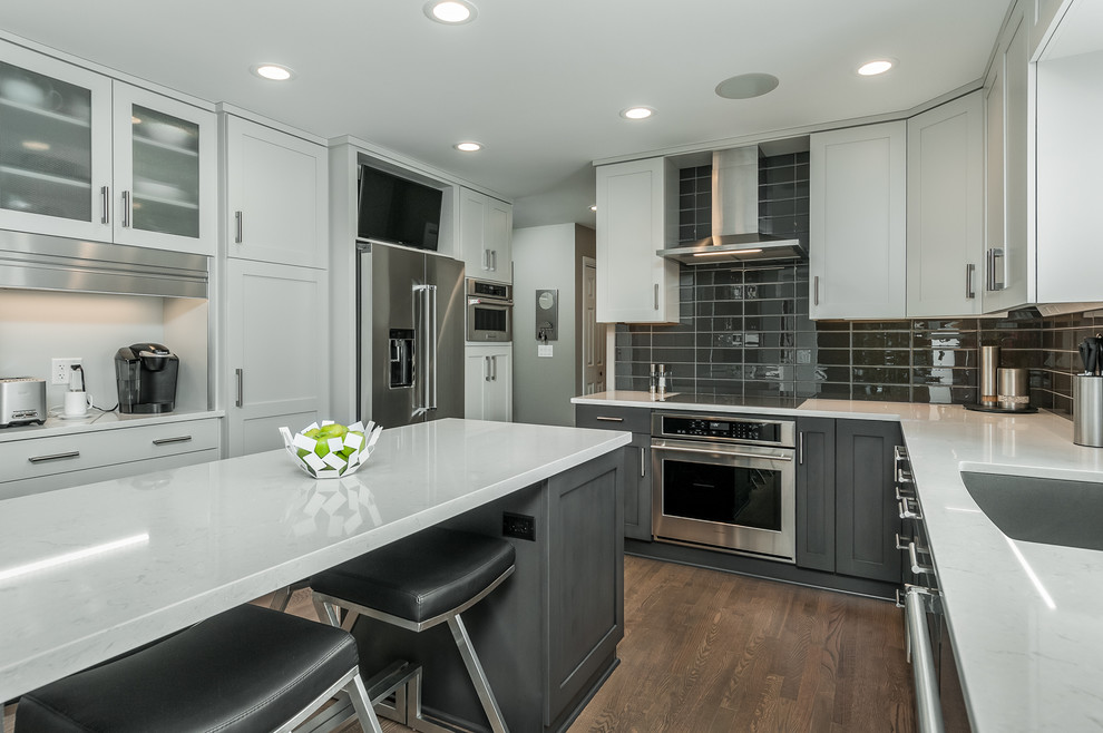 This is an example of a small transitional u-shaped separate kitchen in Other with an undermount sink, shaker cabinets, grey cabinets, quartz benchtops, grey splashback, glass tile splashback, stainless steel appliances, with island, brown floor, white benchtop and dark hardwood floors.