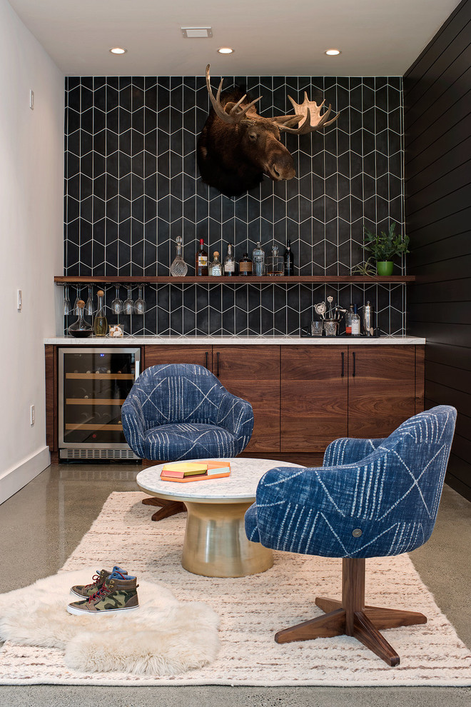This is an example of a contemporary home bar in San Francisco with flat-panel cabinets, dark wood cabinets, black splashback, concrete floors, grey floor and white benchtop.