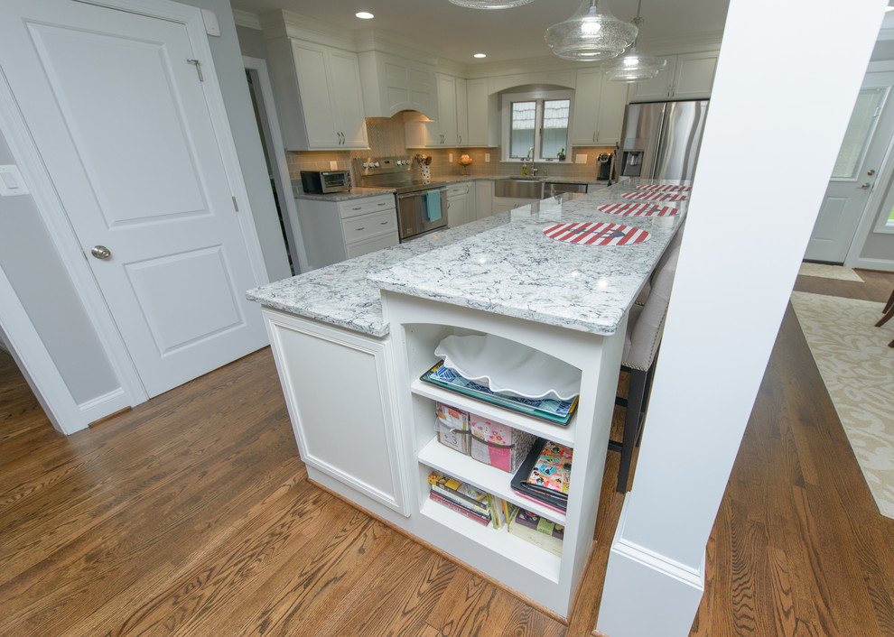 Inspiration for a large transitional l-shaped dark wood floor and brown floor kitchen remodel in Baltimore with a farmhouse sink, recessed-panel cabinets, white cabinets, quartz countertops, gray backsplash, subway tile backsplash, stainless steel appliances and an island
