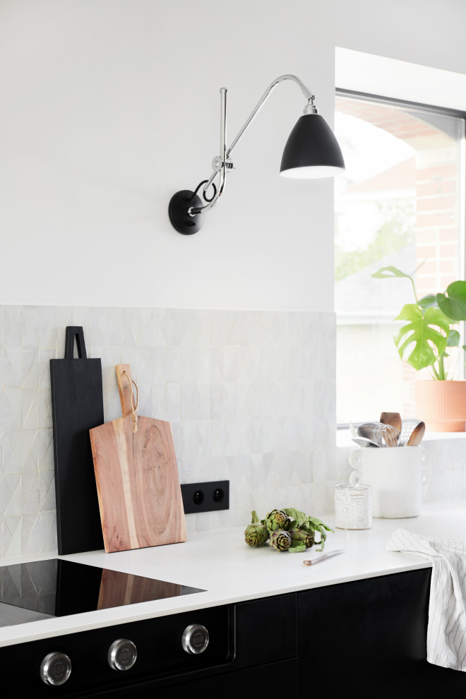 Moderne Küche mit schwarzen Schränken, Mineralwerkstoff-Arbeitsplatte, hellem Holzboden und weißer Arbeitsplatte in Nantes