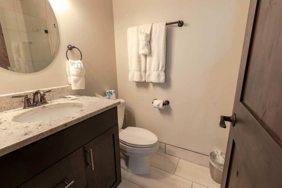Photo of a mid-sized traditional master bathroom in Salt Lake City with shaker cabinets, dark wood cabinets, an alcove shower, a two-piece toilet, beige walls, porcelain floors, an undermount sink, granite benchtops, beige floor and beige benchtops.
