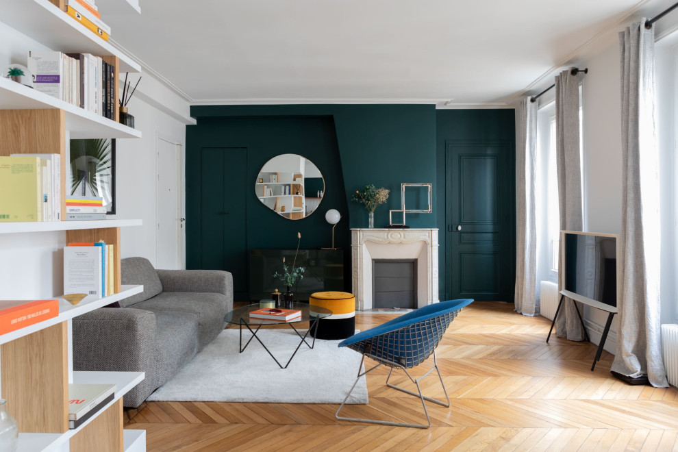 Design ideas for a large scandinavian open concept living room in Paris with a library, green walls, light hardwood floors, a standard fireplace, a freestanding tv and beige floor.