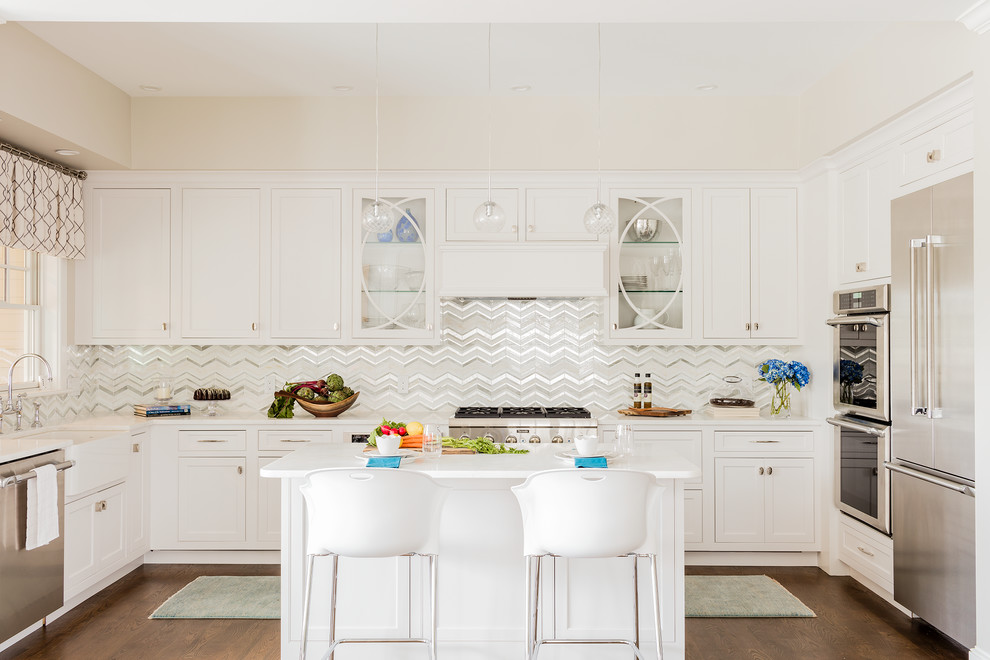 Design ideas for a large contemporary u-shaped kitchen in Boston with a farmhouse sink, shaker cabinets, white cabinets, white splashback, stainless steel appliances, dark hardwood floors, with island, ceramic splashback and quartz benchtops.