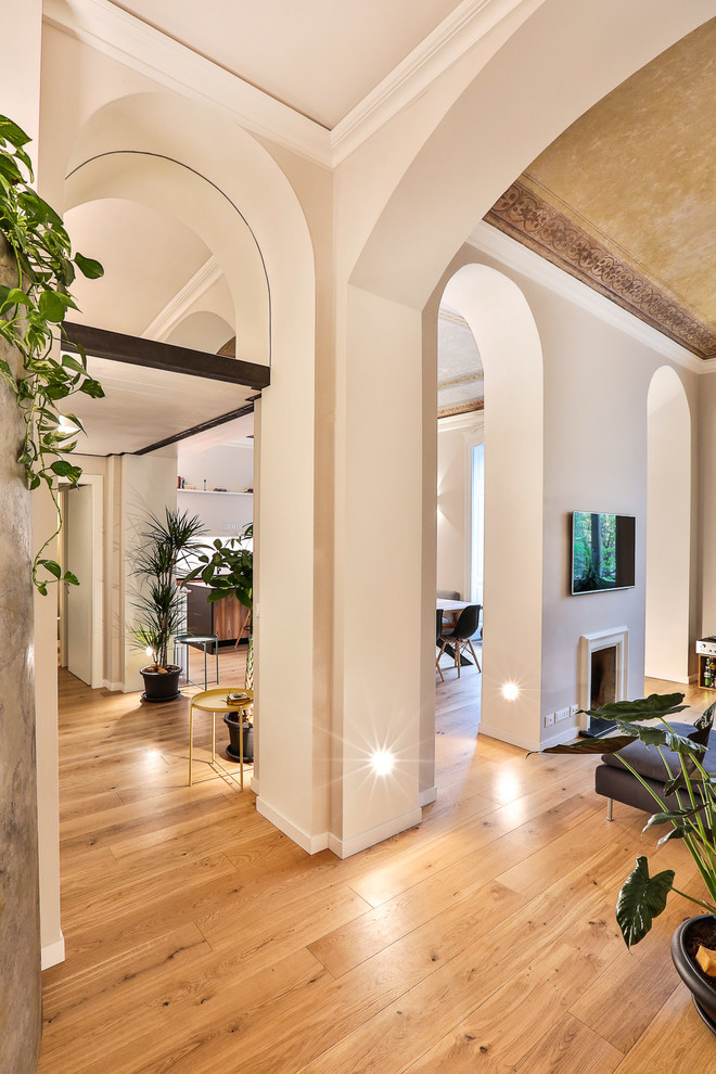 This is an example of a large contemporary hallway in Turin with white walls, medium hardwood floors and brown floor.