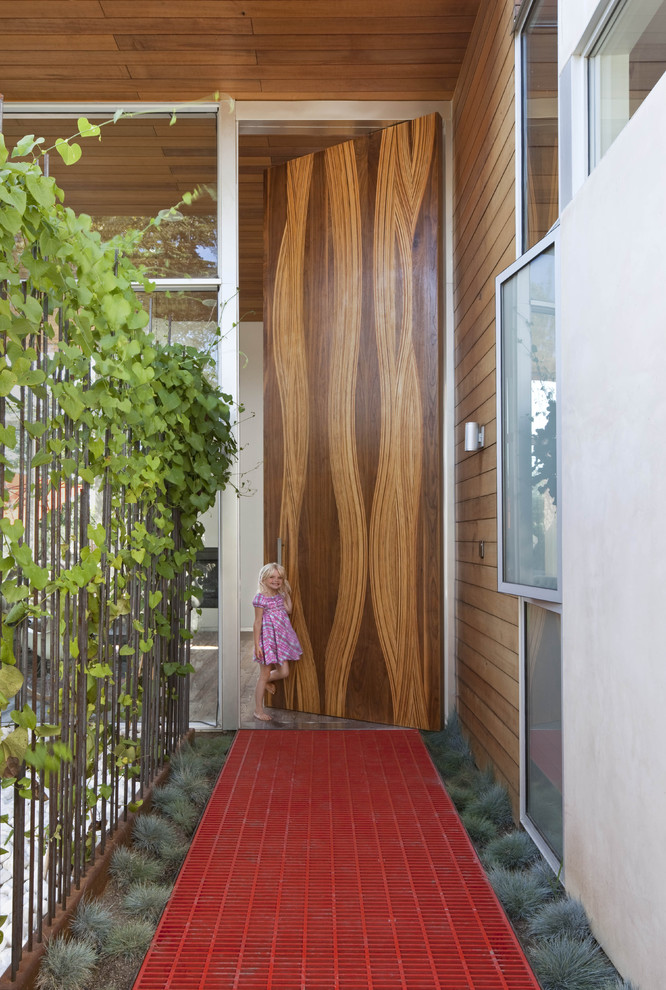 This is an example of an expansive modern front door in Los Angeles with a single front door and a medium wood front door.