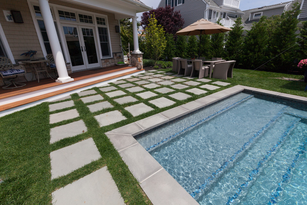 Large beach style backyard full sun garden in New York with a water feature and concrete pavers for summer.