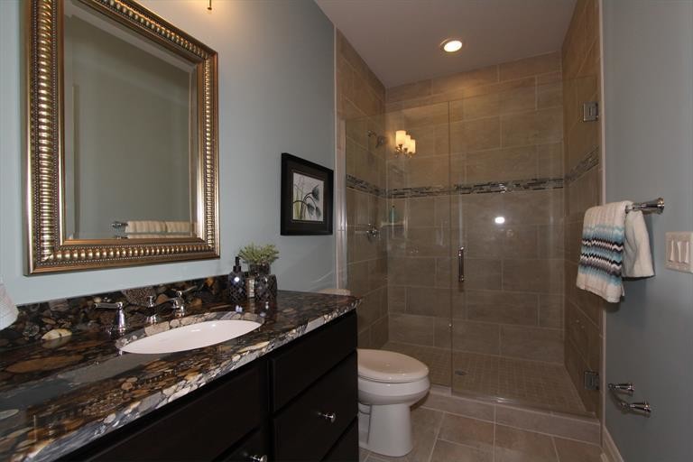 Mid-sized transitional 3/4 bathroom in Cincinnati with an undermount sink, black cabinets, granite benchtops, a curbless shower, a one-piece toilet, beige tile, stone tile, green walls and ceramic floors.