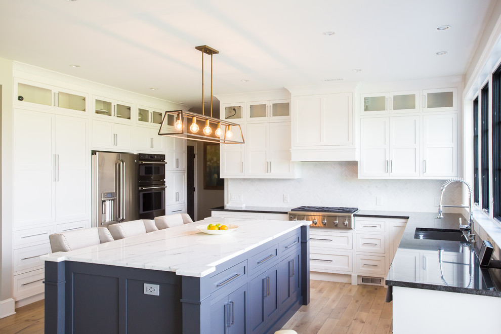 Mid-sized transitional u-shaped medium tone wood floor and brown floor eat-in kitchen photo in Baltimore with an undermount sink, shaker cabinets, white cabinets, marble countertops, white backsplash, marble backsplash, stainless steel appliances, an island and white countertops