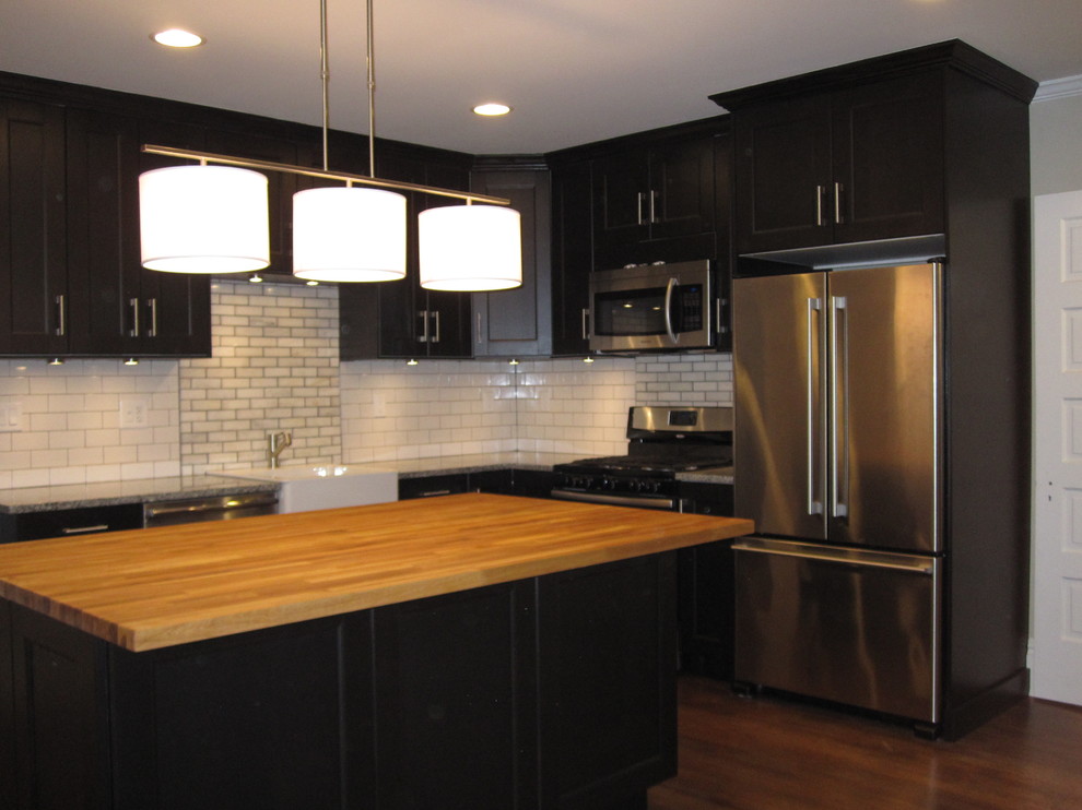 This is an example of a mid-sized transitional l-shaped eat-in kitchen in Philadelphia with a farmhouse sink, beaded inset cabinets, dark wood cabinets, granite benchtops, white splashback, subway tile splashback, stainless steel appliances, medium hardwood floors and with island.