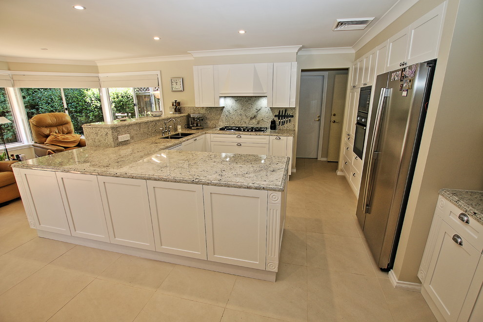 Photo of a large traditional u-shaped eat-in kitchen in Sydney with an undermount sink, shaker cabinets, white cabinets, granite benchtops, multi-coloured splashback, stone slab splashback, stainless steel appliances, ceramic floors and a peninsula.