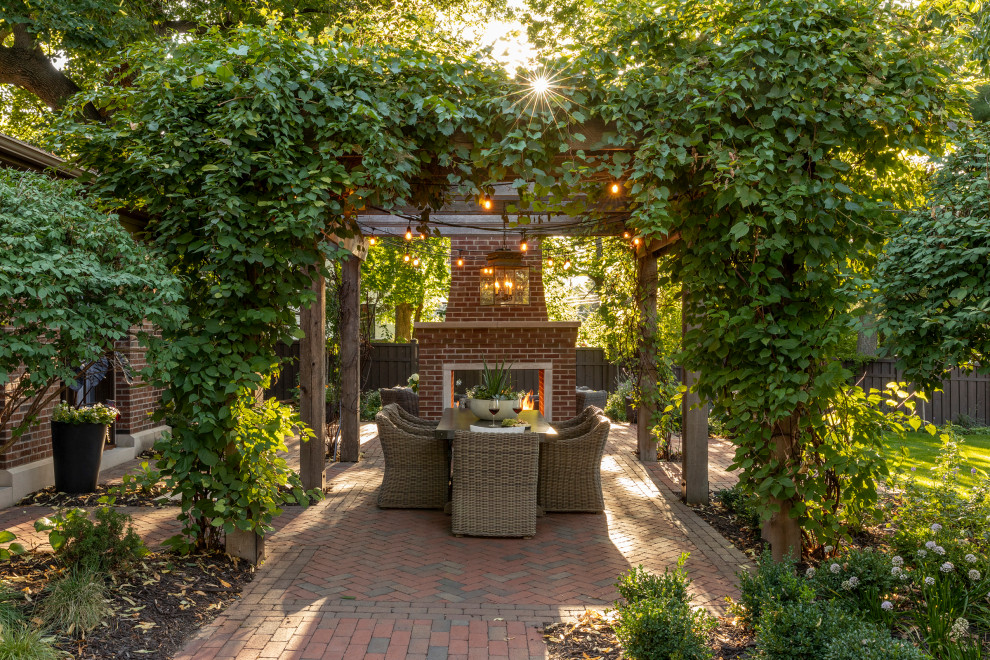 Small classic back patio in Minneapolis with a fireplace, brick paving and a pergola.