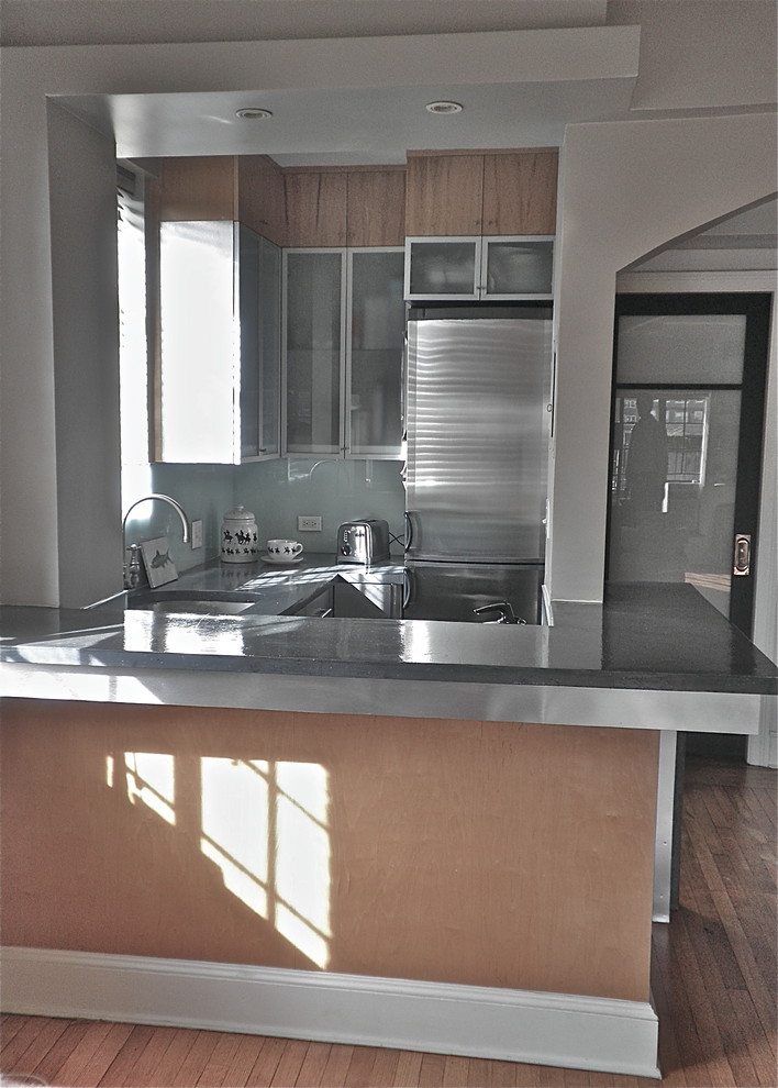 Small contemporary u-shaped separate kitchen in New York with a drop-in sink, flat-panel cabinets, stainless steel cabinets, concrete benchtops, green splashback, glass sheet splashback and stainless steel appliances.