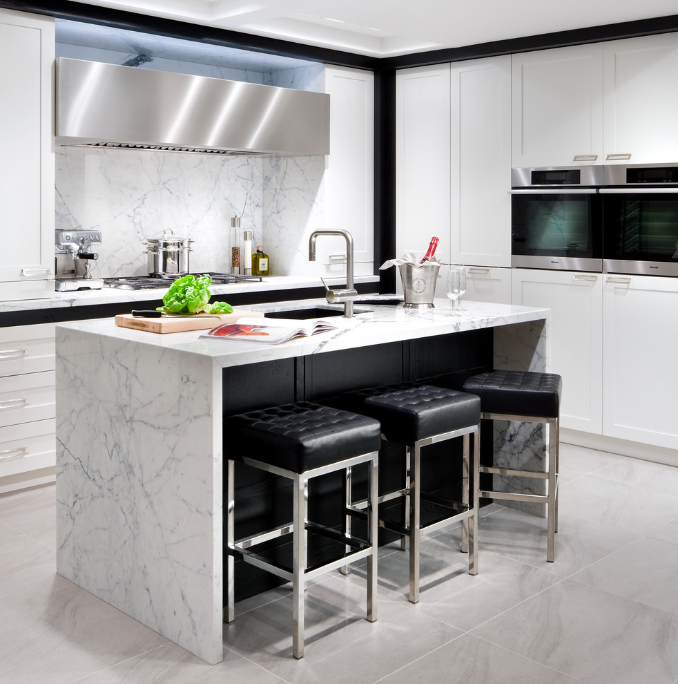Photo of a transitional l-shaped kitchen in Toronto with an undermount sink, shaker cabinets, white cabinets, white splashback and stainless steel appliances.