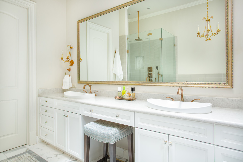 Photo of a large traditional master bathroom in Dallas with recessed-panel cabinets, white cabinets, a freestanding tub, a corner shower, a two-piece toilet, gray tile, ceramic tile, beige walls, marble floors, a vessel sink, engineered quartz benchtops, multi-coloured floor, a hinged shower door and white benchtops.