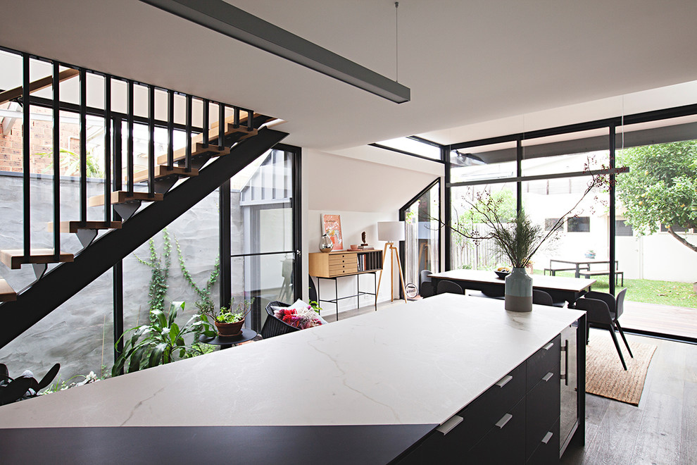 Small contemporary open plan kitchen in Melbourne with marble benchtops, dark hardwood floors and with island.