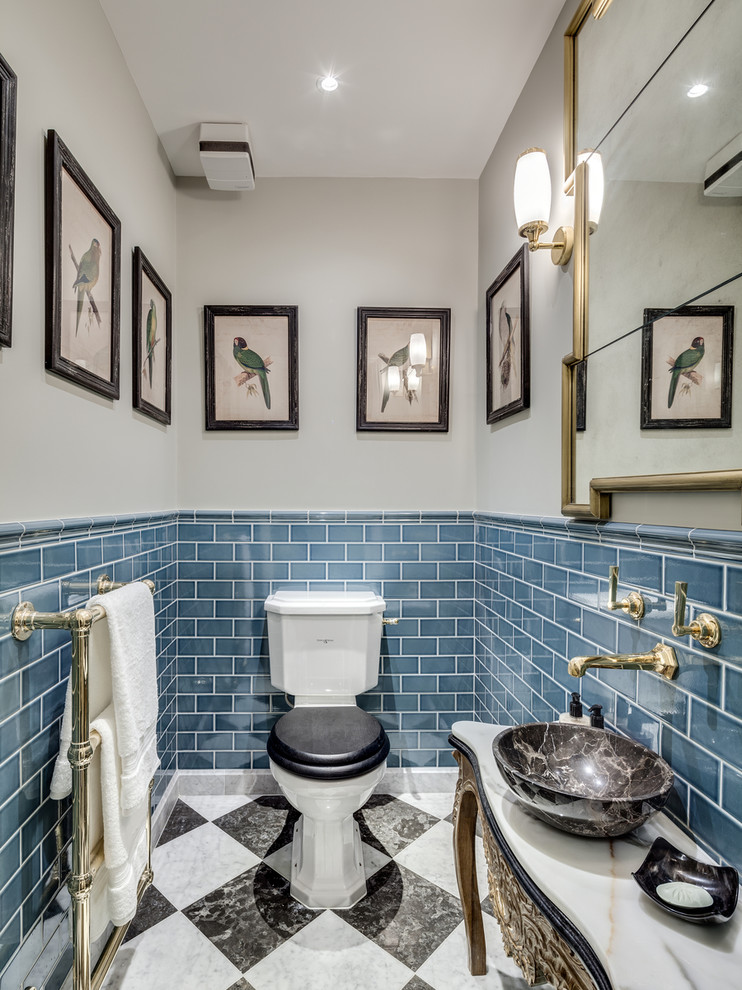 This is an example of a small traditional powder room in London with a vessel sink, a two-piece toilet, blue tile, subway tile, grey walls, marble floors and furniture-like cabinets.
