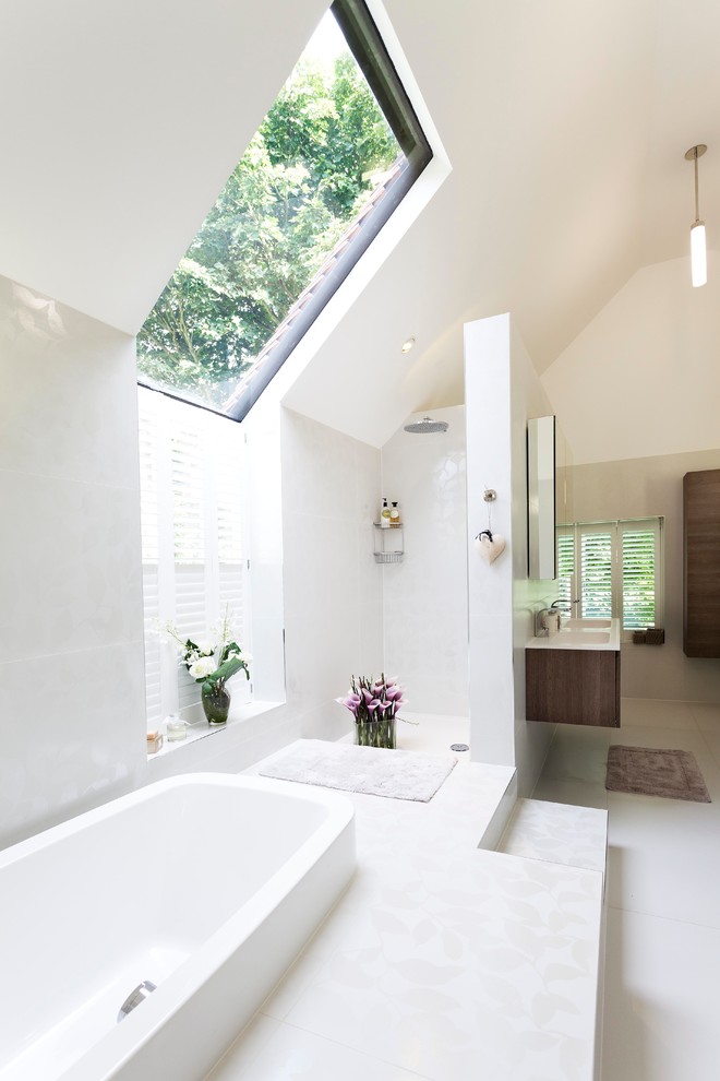 This is an example of a large contemporary master bathroom in Oxfordshire with a wall-mount sink, a drop-in tub, an open shower, white tile, white walls, a wall-mount toilet, porcelain tile, porcelain floors and an open shower.