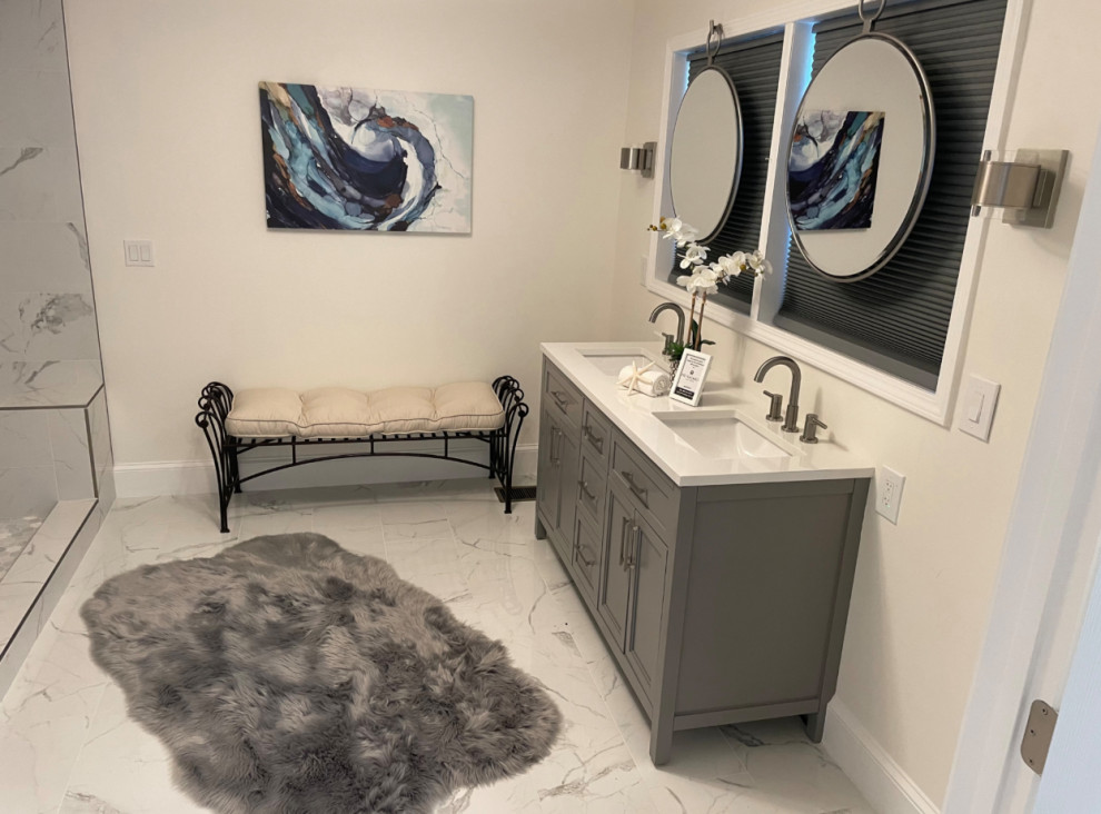 Modern bathroom vanity with double sinks, round mirrors, gray cabinetry, wall art, bench, and plush rug.