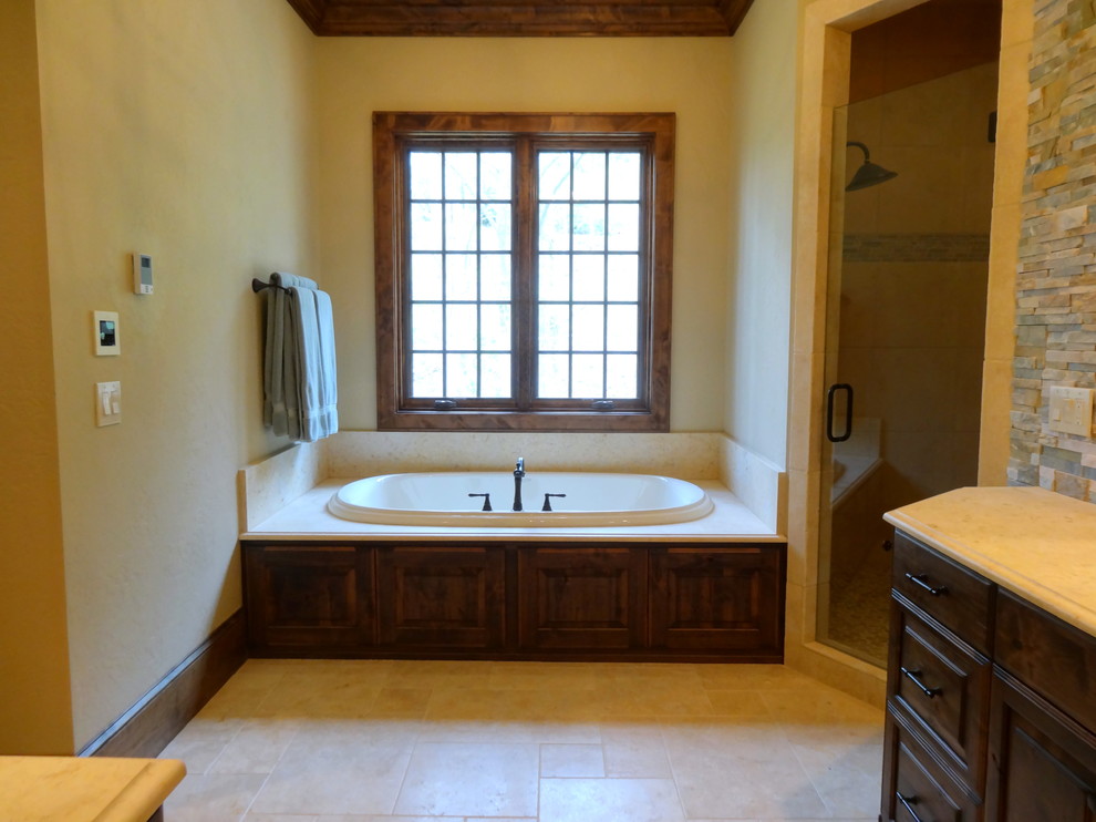 Photo of an expansive country master bathroom in Charlotte with an undermount sink, raised-panel cabinets, dark wood cabinets, granite benchtops, an alcove tub, an alcove shower, a two-piece toilet, multi-coloured tile, stone tile, beige walls and ceramic floors.