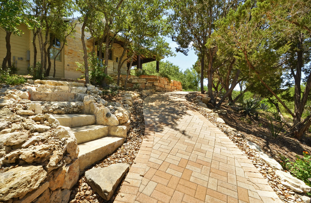 Inspiration for a large country sloped garden in Austin with a retaining wall and brick pavers.