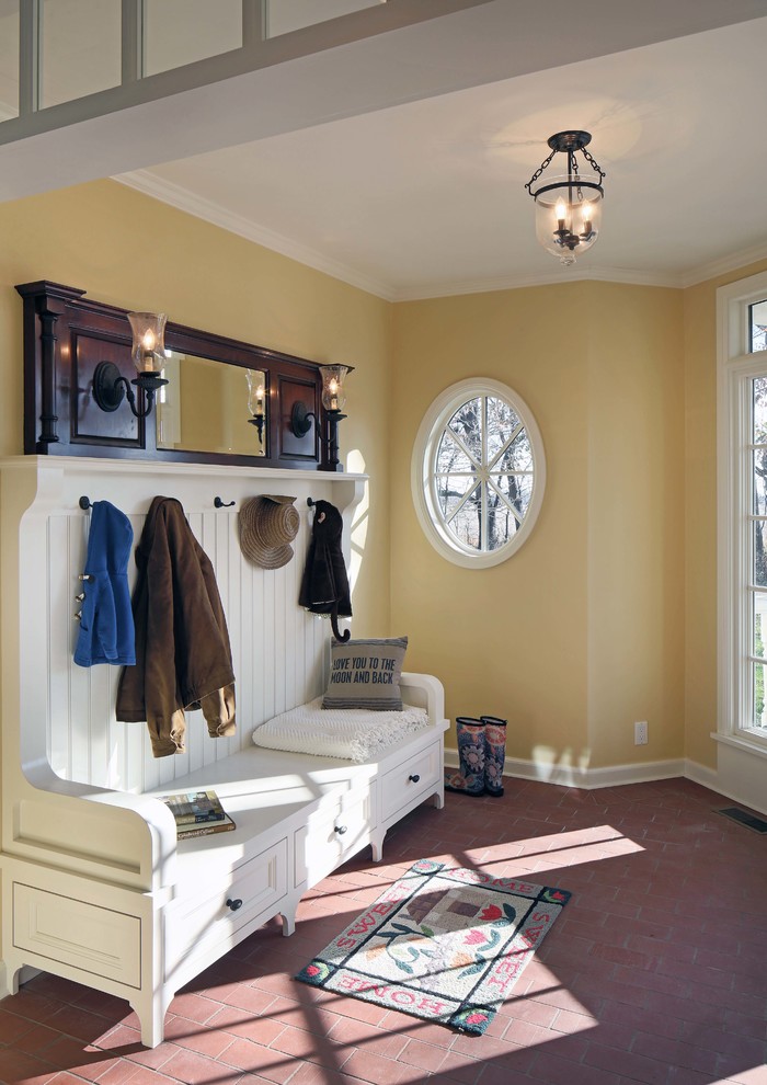 Photo of a country mudroom in Omaha with yellow walls and brick floors.