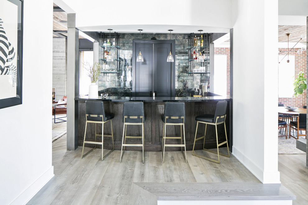 Country seated home bar in Los Angeles with open cabinets, grey splashback, light hardwood floors, brown floor and black benchtop.