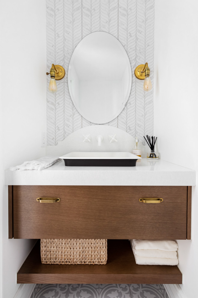 This is an example of a small beach style powder room in Montreal with flat-panel cabinets, medium wood cabinets, a one-piece toilet, white tile, slate, white walls, porcelain floors, a vessel sink, engineered quartz benchtops, grey floor, white benchtops and a built-in vanity.