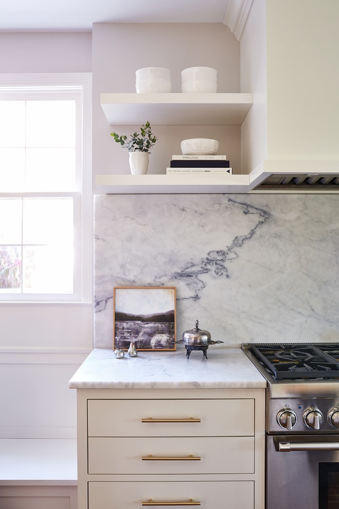 Inspiration for a mid-sized traditional single-wall eat-in kitchen in Cleveland with an undermount sink, flat-panel cabinets, white cabinets, marble benchtops, white splashback, marble splashback, panelled appliances, medium hardwood floors, with island, brown floor and white benchtop.
