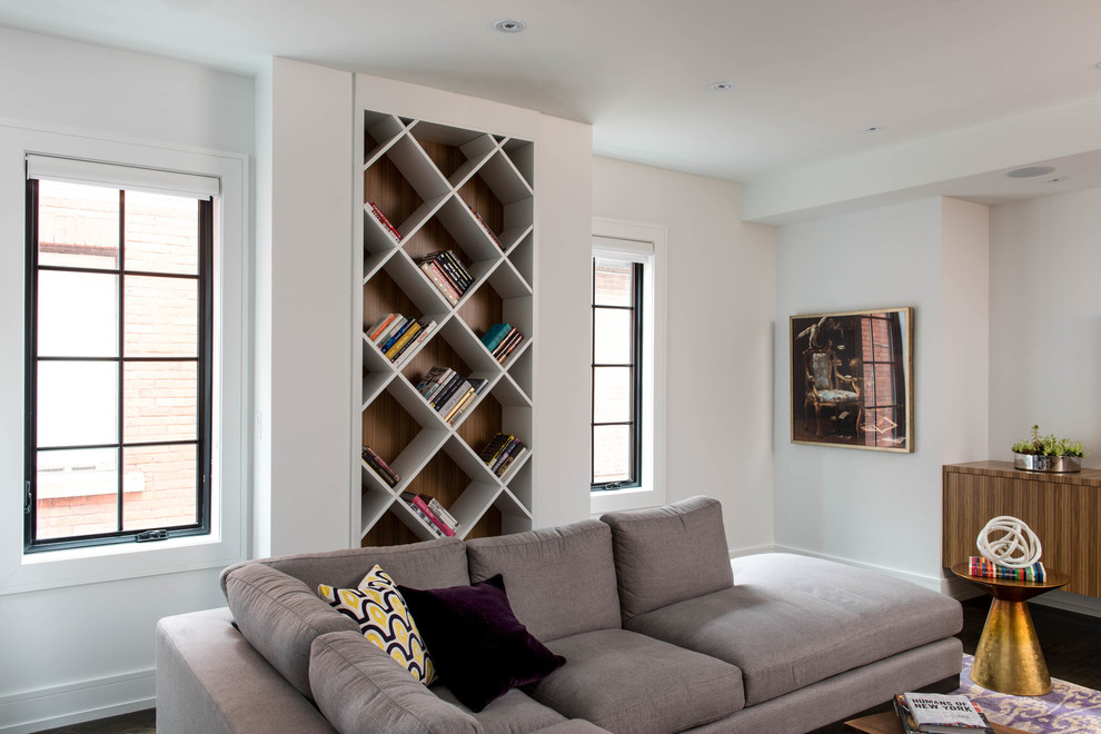This is an example of a contemporary family room in Toronto with a library, white walls and dark hardwood floors.