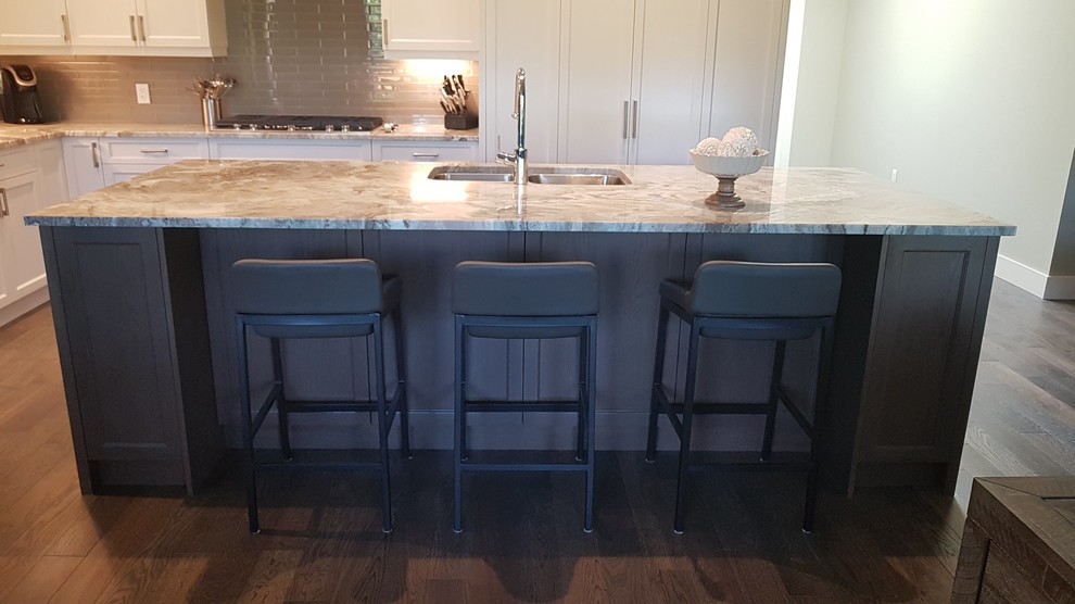 This is an example of a large transitional l-shaped eat-in kitchen in Vancouver with shaker cabinets, granite benchtops, grey splashback, with island, an undermount sink, stainless steel appliances, brown floor, brown benchtop, white cabinets, ceramic splashback and medium hardwood floors.
